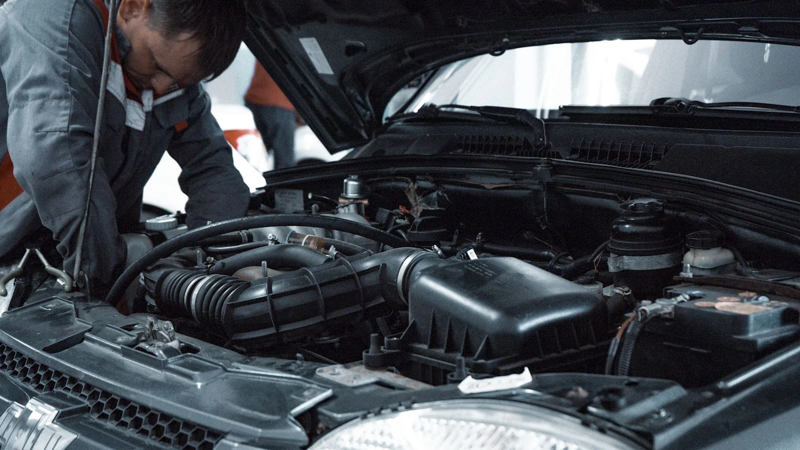 An automotive technician looking into the hood of a car